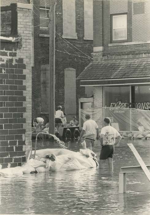 Portraits - Group, Floods, history of Iowa, Iowa History, Motorized Vehicles, Businesses and Factories, Civic Engagement, store, brick building, Waverly, IA, tarp, Iowa, Cities and Towns, power lines, sandbag, Waverly Public Library