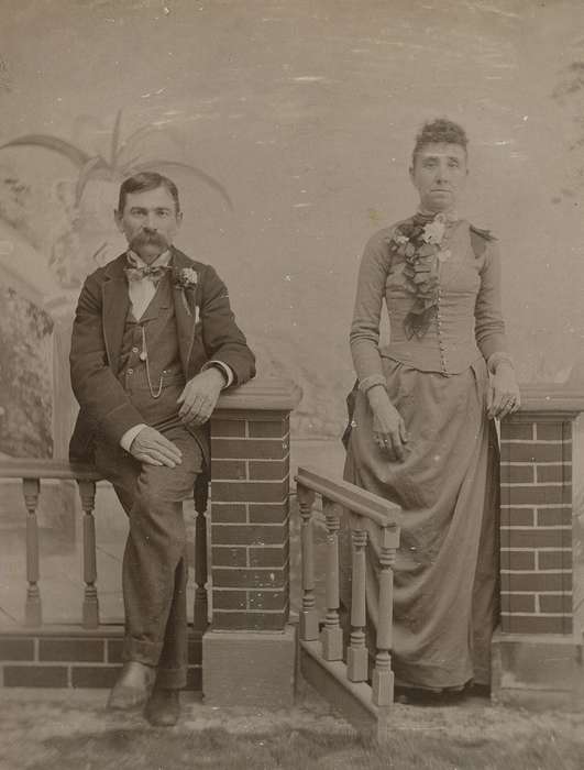 sack coat, woman, watch chain, fence, frizzy bangs, wedding, bow tie, cabinet photo, man, history of Iowa, Iowa History, Portraits - Group, handkerchief, Weddings, Iowa, couple, Olsson, Ann and Jons, Manchester, IA, painted backdrop, mustache, corsage