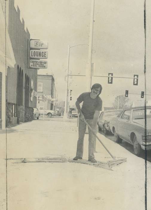 Cities and Towns, Portraits - Individual, lounge, Labor and Occupations, Winter, Waverly Public Library, Main Streets & Town Squares, snow removal, Waverly, IA, history of Iowa, Iowa, sidewalk, man, Iowa History, Businesses and Factories, car, shoveling