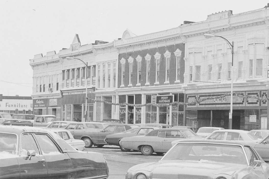 Main Streets & Town Squares, Bloomfield, IA, history of Iowa, Iowa History, Lemberger, LeAnn, Winter, Motorized Vehicles, Businesses and Factories, storefront, store, car, parking lot, street light, Iowa, Cities and Towns, sign