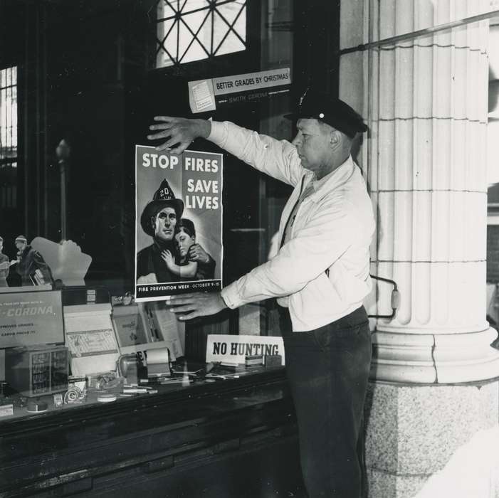 worker, uniform, Businesses and Factories, window display, man, Cities and Towns, box, hat, building interior, Waverly Public Library, Main Streets & Town Squares, history of Iowa, Iowa History, Waverly, IA, fireman, display case, Iowa, collumns, correct date needed, pillar, Portraits - Individual