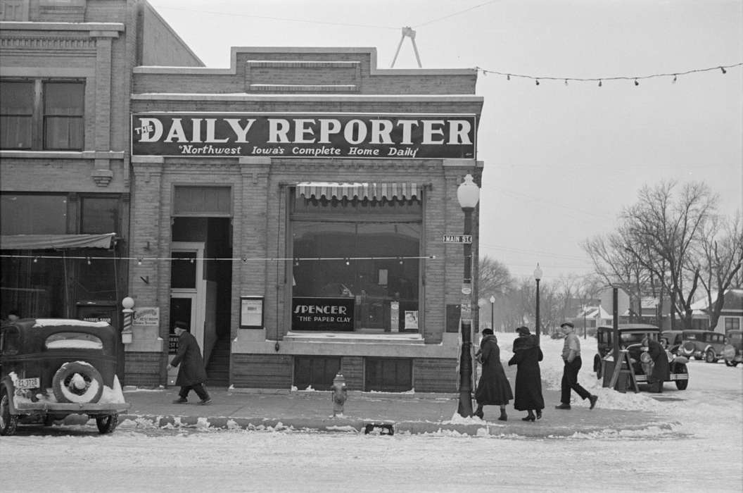 history of Iowa, Iowa History, Library of Congress, Winter, Motorized Vehicles, Businesses and Factories, storefront, sidewalk, car, Iowa, Cities and Towns, lamppost, string lights, snow, lightpost