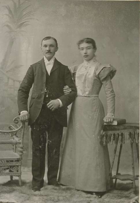 Portraits - Group, Iowa, couple, table, chair, watch chain, Olsson, Ann and Jons, book, tablecloth, Cedar Falls, IA, painted backdrop, history of Iowa, cabinet photo, wicker chair, Iowa History