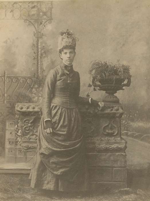 bustle, Iowa, vase, flowers, woman, fingerless mitts, hat, Olsson, Ann and Jons, Portraits - Individual, history of Iowa, fence, painted backdrop, Clarence, IA, cabinet photo, ribbon, Iowa History